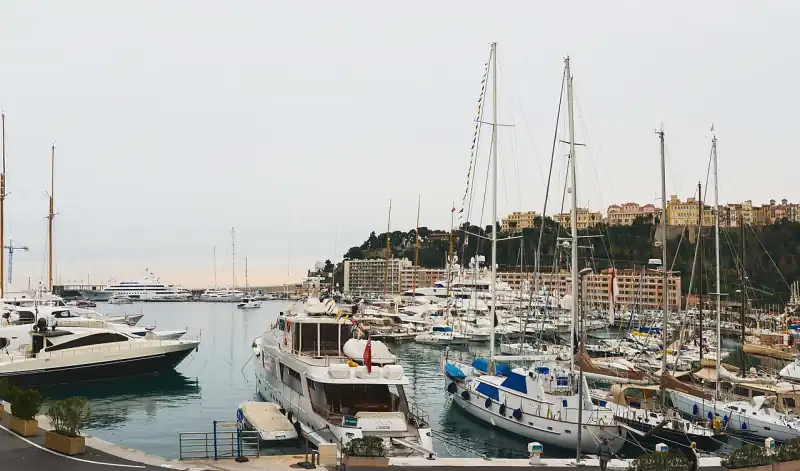 Jachtok a monacói Port Hercule kikötőjében, háttérben a monacói Szikla